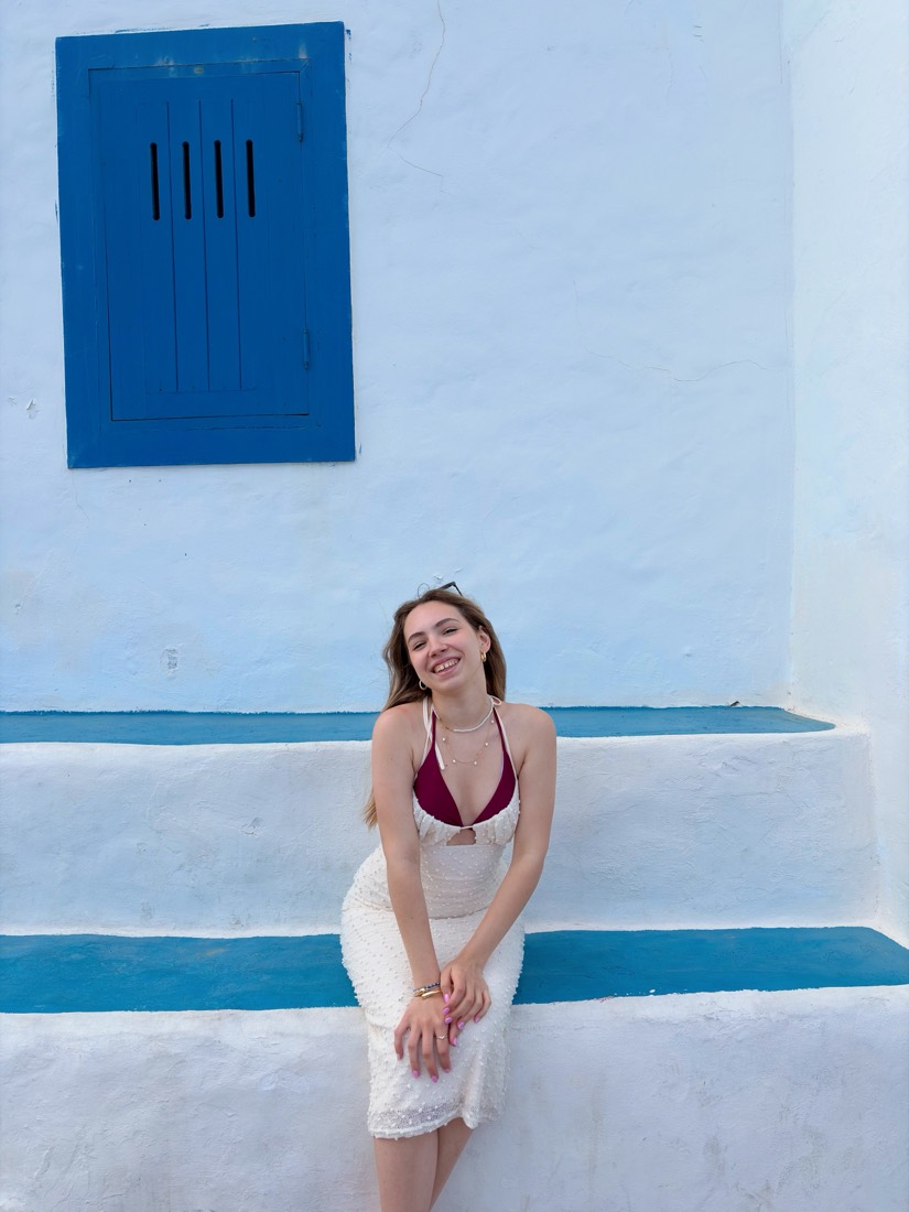 Judith sonriendo en unas escaleras blancas junto al mar